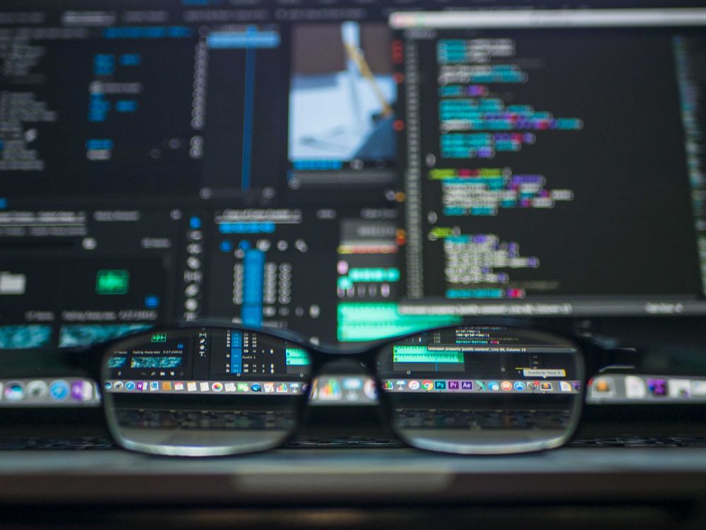 Concept photo of eyeglasses reflecting code, not a product screenshot